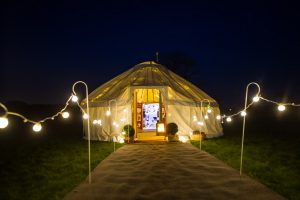 22ft yurt at night with festoon lighting walkway