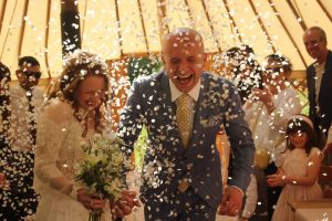 bride and groom smiling under confetti in yurt